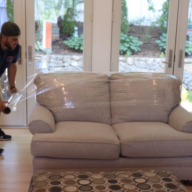Boston Best Rate Movers crew member wrapping a sofa for protection