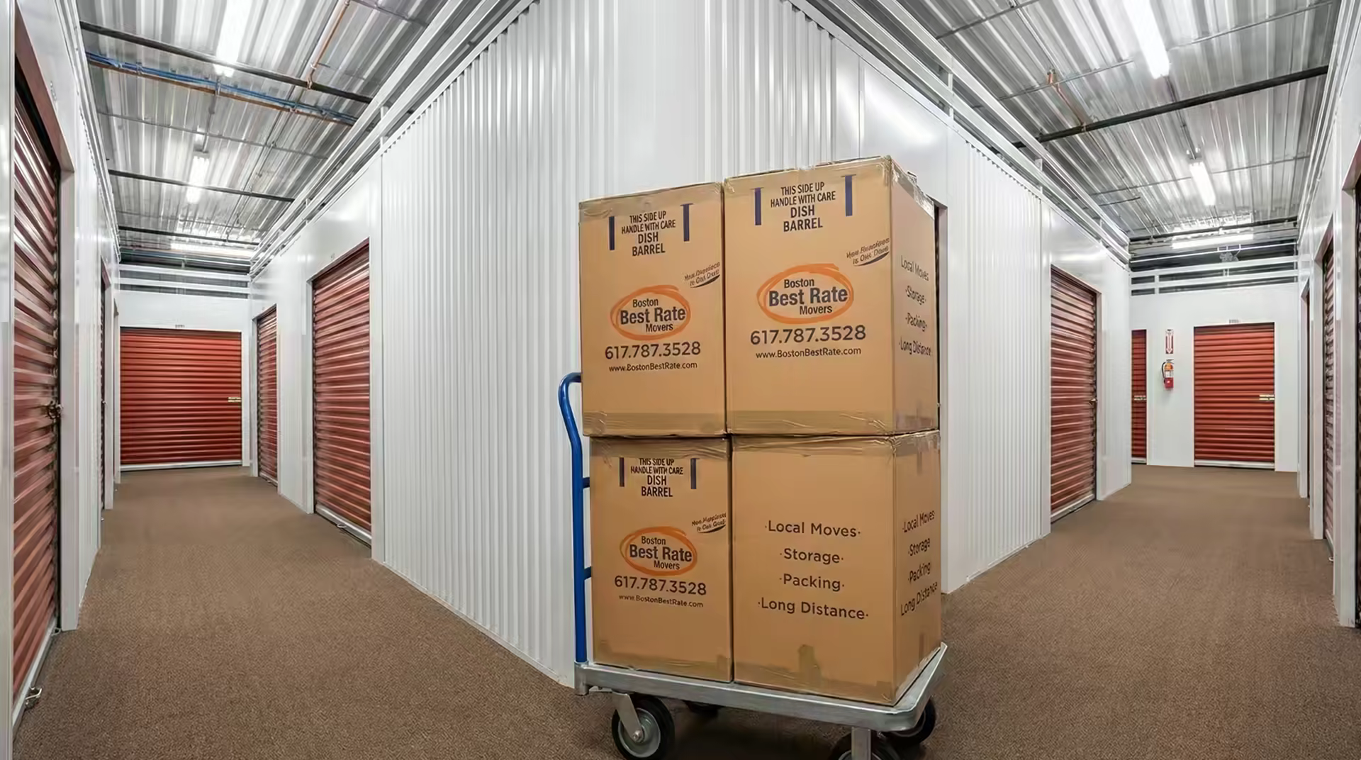 Boston Best Rate Movers branded boxes on a dolly inside a climate-controlled storage facility with red roll-up doors