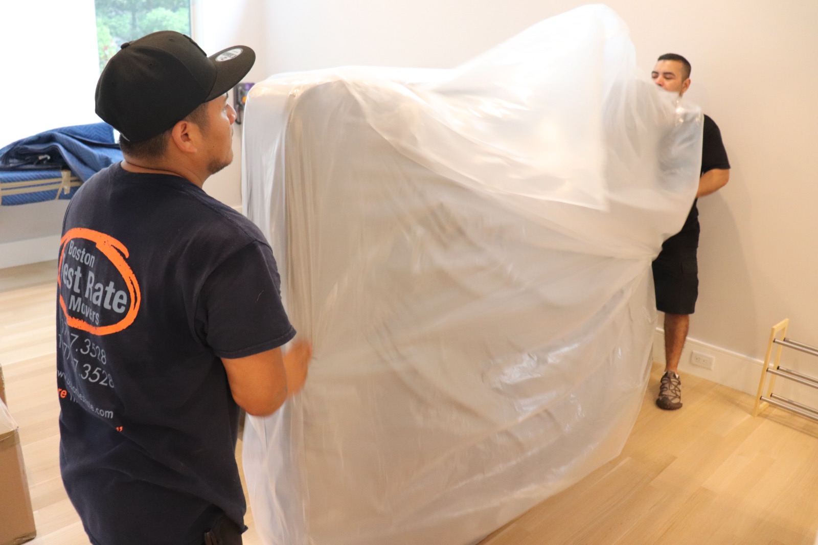 Two Boston Best Rate Movers crew members wrapping a mattress for protection