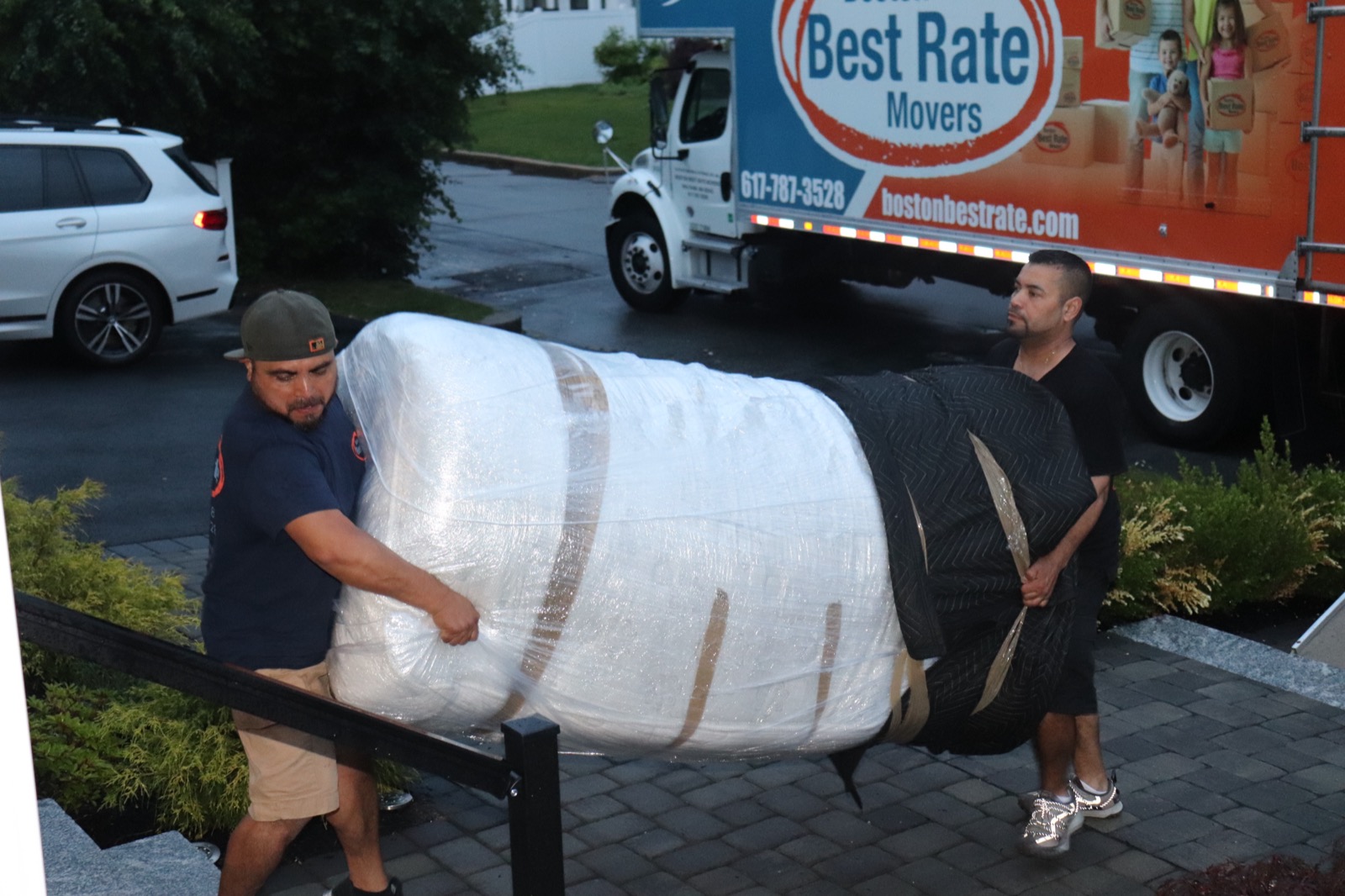 Boston Best Rate Movers crew carrying wrapped furniture to the home