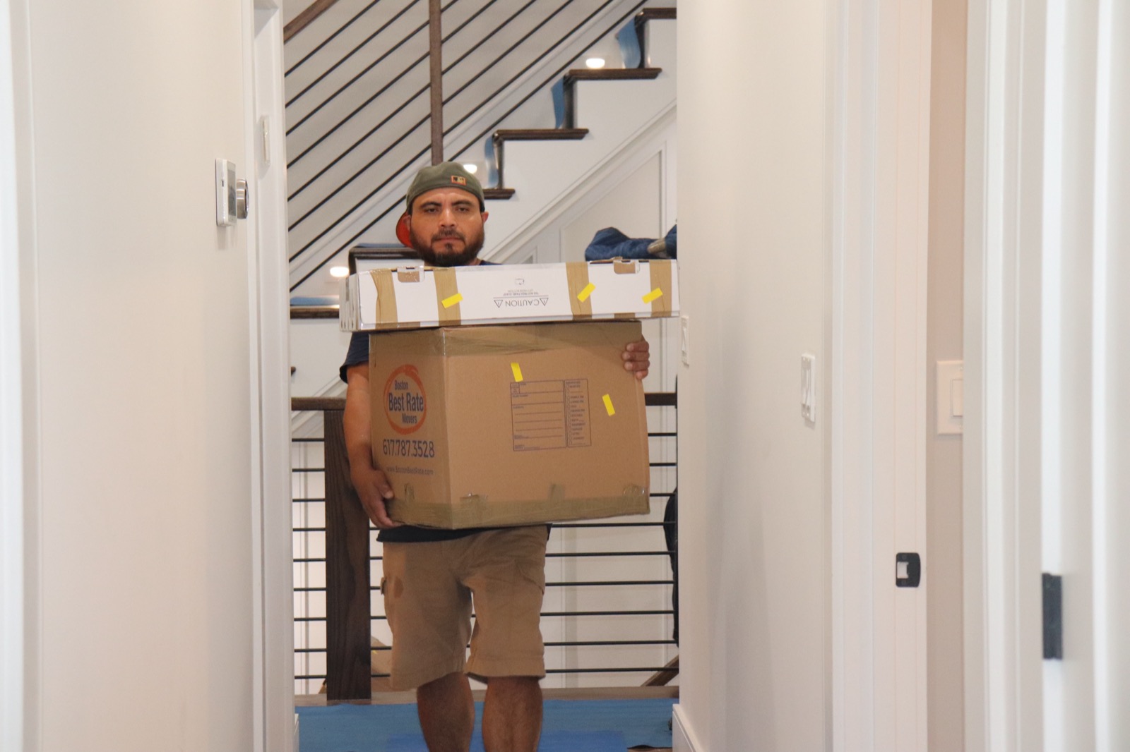 Boston Best Rate Movers crew member carrying boxes through a hallway