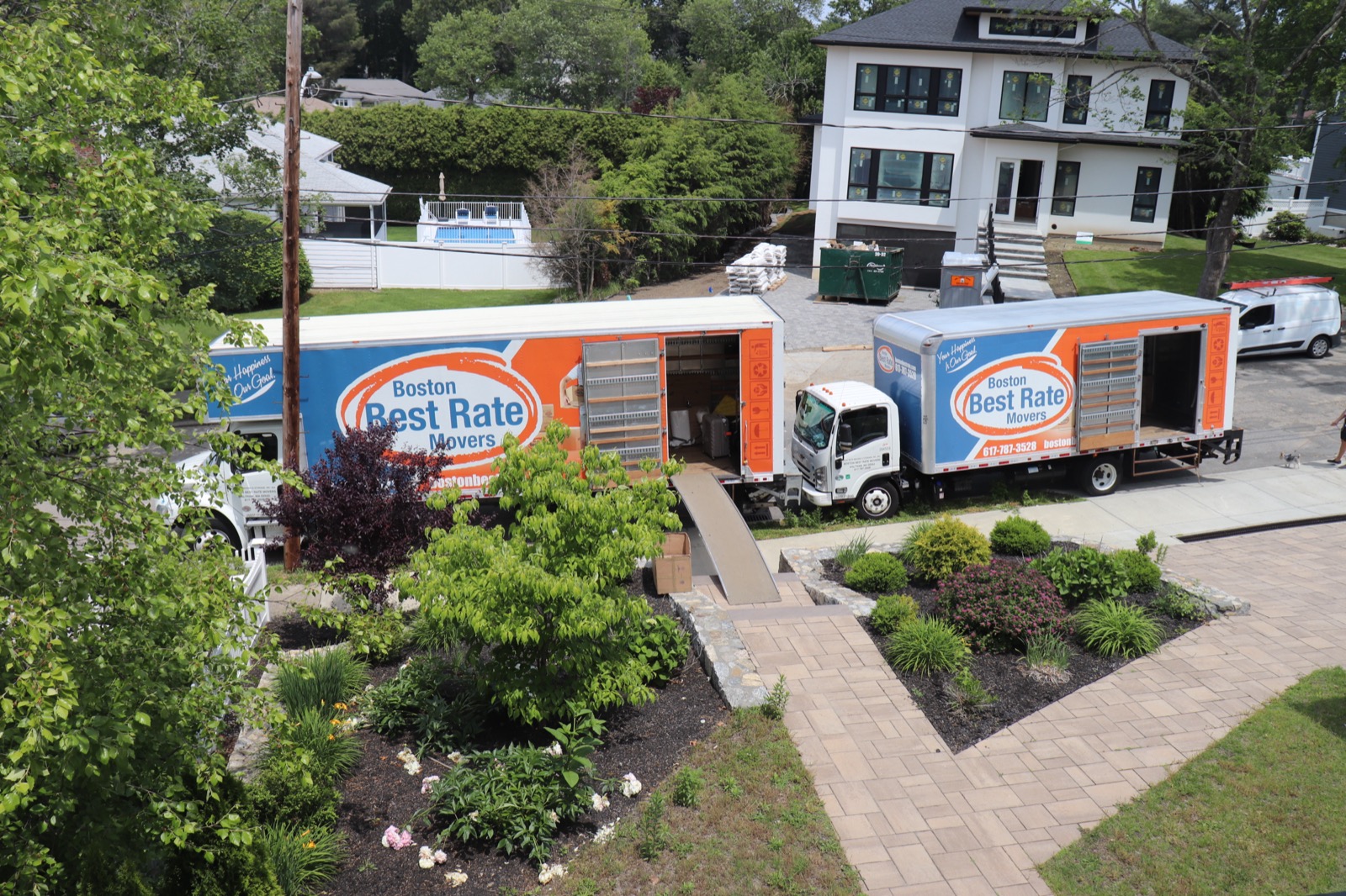 Two Boston Best Rate Movers trucks at a residential move, aerial view